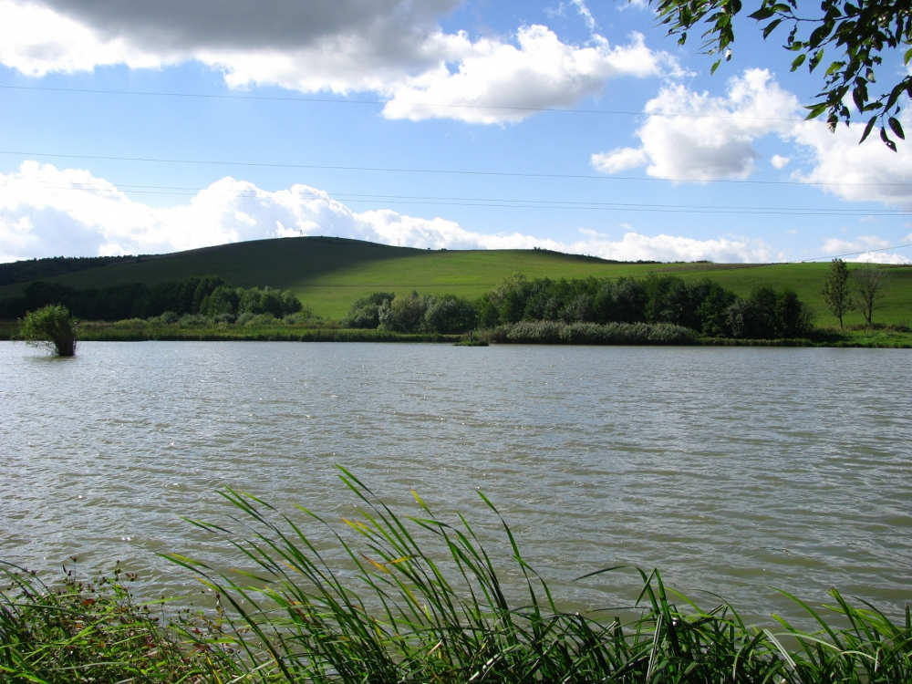 Panorama stawu w Besku wśród zielonych wzgórz